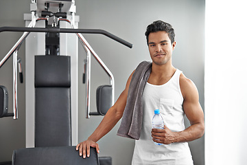 Image showing Gym, machine and portrait of man with water bottle for recovery after exercise for body building. Healthy, fitness and person relax after workout with hydration for benefits to muscle and wellness