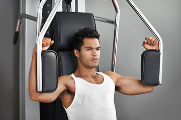 Image showing Fitness, resistance exercise and man in gym for arm muscle training for health, wellness and strength. Active, body and young male athlete on machine with weights for bodybuilding in sports center.