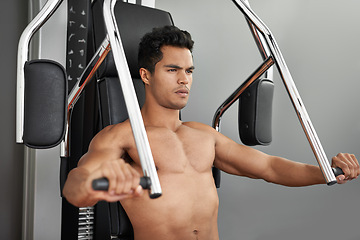 Image showing Workout, resistance exercise and man in gym for arm muscle training for health, wellness and strength. Active, body and young male athlete on machine with weights for bodybuilding in sports center.