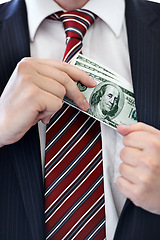 Image showing Businessman, hands and money bribe in pocket for fraud, scam or secret on a white studio background. Closeup of employee with cash, dollar bills or finance in bribery, deal or financial exchange