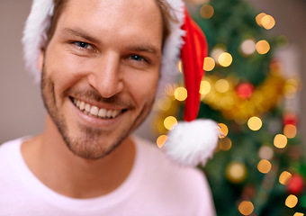 Image showing Man, party hat and portrait by Christmas tree, celebration and smiling at home on religious holiday. Male person, happy and special decoration for festive vacation, tradition and cheerful for event