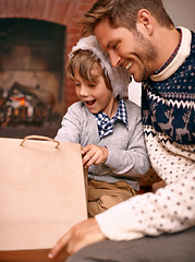 Image showing Father, son and opening gift on Christmas, curiosity and happy for celebrating a festive holiday. Daddy, child and bonding on religious vacation in living room, childhood and tradition of present