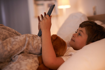 Image showing Boy, child and tablet in bedroom at night for typing, reading or online game with app in family home. Kid, bed and digital touchscreen for movie, cartoon and streaming subscription to relax in house