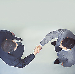 Image showing Businessman, handshake and partnership above for agreement, deal or meeting on a gray studio background. Top view of man, colleagues or employees shaking hands for b2b or teamwork on mockup space