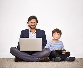 Image showing Father, happy kid and portrait with laptop, tablet and learning with boy at home by wall. Smile, child and dad on computer with tech for remote work, love or connection of family together on floor