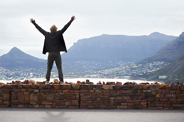 Image showing Person, watching and mountains with arms up in freedom and standing on brick wall in Cape Town. Excited, tourist or traveler with hands in the air for happiness on vacation, holiday or road trip