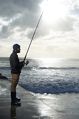 Image showing Thinking, fishing and man at a beach with pole for water hobby, recreation or stress relief vacation in nature. Casting, rod and fisherman at sea for travel, adventure or fisher sports in Cape Town