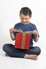 Image showing Sitting child opening a present