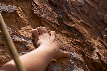 Image showing Person, hand and rock climber with rope on mountain for climbing, hiking or grip in extreme sports. Closeup of hiker or mountaineer grabbing patch, hole or pattern on natural surface for fitness