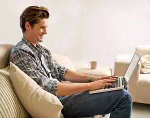 Image showing Laptop, relax and man on sofa in home for watching videos, online networking and website research. Happy, smile and person with computer for internet, remote work and typing email in living room
