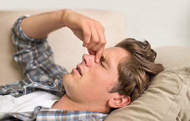 Image showing Man, nose and headache pain on sofa or sinus problem with fatigue or allergy infection, sick or bacteria. Male person, unhappy and tired migraine in London home or flu disease or stress, bug or dizzy