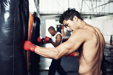 Image showing Fitness, punching bag and man with boxing gloves at a gym for training, resilience or performance. Sports, body and male boxer profile with punch practice for strength, energy for fighting exercise