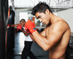 Image showing Punching bag, fitness and man with boxing gloves at a gym for training, resilience or performance. Sports, body and male boxer profile with punch practice for strength, energy for fighting exercise