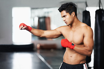 Image showing Man, training and gloves in gym for combat match, practice and determined for competition to win. Light weight champion, workout and focus for tough sport, fitness and exercise with endurance for mma