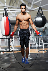 Image showing Portrait, fitness and man skipping in gym for fight preparation, training or boxing cardio. Exercise, workout or strong body of shirtless young athlete with jump rope for combat sports competition