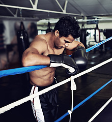 Image showing Sports, break and man boxer in gym for exercise, workout and combat training for competition. Breathing, health and shirtless male athlete fighter in boxing ring with gloves in fitness center.