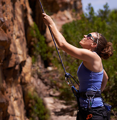 Image showing Happy woman, climber and mountain with rope for climbing, hiking or trekking on rocks in nature. Female person or hiker with smile and harness for grip, safety or extreme sports in fitness challenge