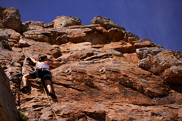 Image showing Female person, rock climbing and outdoors for adventure, fitness and exercise in the sun for extreme sports. Woman, low angle and nature for wellness, mountain and fearless activity for strength