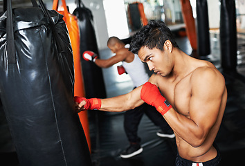 Image showing Punching bag, man and fitness with boxing gloves at a gym for training, resilience or performance. Sports, body and male boxer profile with punch practice for strength, energy for fighting exercise
