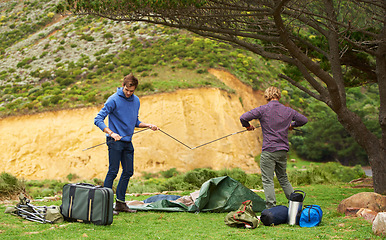 Image showing Camping, men and friends with tent for assemble on grass in nature with equipment for holiday and vacation. People, getting ready and campsite in woods for adventure, travel and bonding in forest