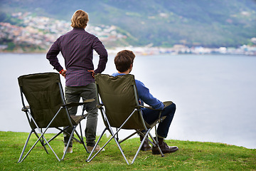 Image showing Camping, chair and people relax at lake with landscape in countryside, nature or calm vacation. Summer, holiday and back of friends sitting on grass at river with peace in environment together