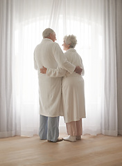 Image showing Senior couple, hug and relaxing by window in retirement, love and bonding in pajamas on holiday. Elderly people, back and embracing for affection in marriage, romance and morning routine at home