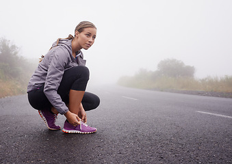 Image showing Fitness, woman and tie shoes on road outdoor to prepare for exercise, training or workout with fog in winter. Sports, serious person and tying sneakers, thinking and getting ready on mockup space