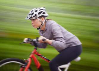 Image showing Woman, bike and nature with ride, speed and fitness for health and wellness or workout. Athlete, cycling and exercise for training, transportation and adventure with helmet for cardio and motion blur