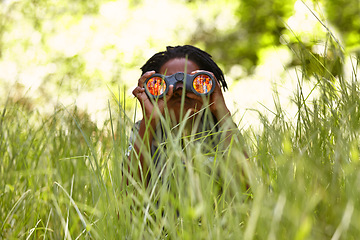 Image showing Nature, binoculars and child in grass for exploring in park on vacation, adventure or holiday. Travel, forest and young boy kid with equipment in lawn in outdoor field or woods on weekend trip.