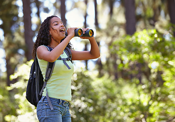 Image showing Happy girl, binoculars and nature with backpack for sightseeing, explore or outdoor vision. Young female person, child or teenager enjoying sight, adventure or bird watching and search in forest