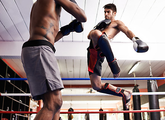 Image showing Kickboxing, jump in fight and men training for fitness and sport in gym, coach and athlete with workout and action. Energy, challenge and MMA with athlete in ring for boxing, exercise and endurance