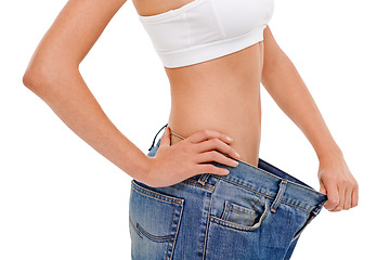 Image showing Diet, health and woman with big pants in studio for weight loss, fitness or exercise results. Wellness, body and closeup of female person with jeans for measuring slim stomach by white background.