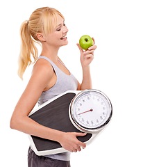 Image showing Scale, smile and woman with apple for diet, benefits or food to lose weight in studio. Healthy eating, nutrition and happy with girl with fruit for body wellness, weightloss and white background