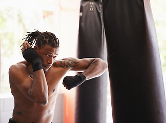 Image showing Fitness, punching bag and black man in boxing gym for exercise, challenge or competition training. Power, muscle and serious champion boxer at workout with confidence, fight and energy in sports club