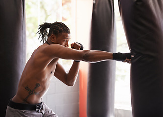 Image showing Fitness, punching bag and black man in gym for exercise, boxing challenge or competition training. Power, muscle and serious champion boxer at workout with confidence, fight and energy in sports club
