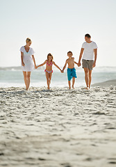 Image showing Parents, children and beach on vacation in summer with holding hands and smile for happiness in Florida. Family, adventure and travel for holiday with kids to relax, fun and enjoy trip in seaside.