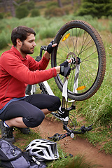 Image showing Exercise, bicycle and fixing wheel with man cyclist in countryside for sports, hobby or cardio training. Fitness, cycling or tyre puncture with young athlete and bike outdoor in nature for workout