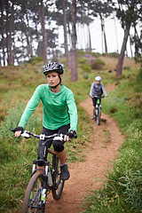 Image showing Woman, bike and cycling outdoor on trail for exercise, workout or adventure in forest with fitness. People, cyclists and bicycle with helmet in woods or off road for sport, hobby and travel in nature