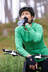 Image showing Woman, drinking water and nature with bicycle for cycling, fitness or break on off road trail or path. Thirsty female person, athlete or cyclist with beverage in forest or rest for outdoor workout