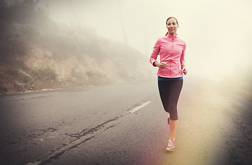 Image showing Nature, health and woman running in fog on mountain road for race, marathon or competition training. Sports, exercise and athlete with cardio workout for fitness in misty outdoor woods or forest.