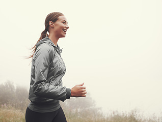 Image showing Nature, energy and woman running in fog on mountain road for race, marathon or competition training. Sports, exercise and athlete with cardio workout for fitness in misty outdoor woods or forest.