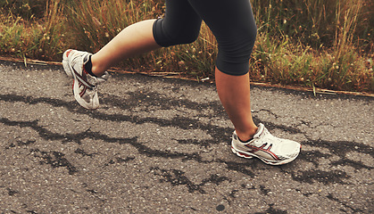 Image showing Legs, running and person on road outdoor for fitness, healthy body and exercise in sneakers. Shoes, sports and athlete jog for cardio, wellness and training for race with energy to workout in nature