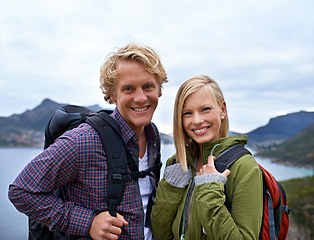 Image showing Happy couple, portrait and hiking with backpack on mountain for sightseeing, travel or outdoor journey in nature. Face of young man, woman or hikers carrying bag for trekking, fitness or adventure