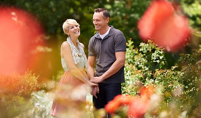 Image showing Love, holding hands and happy couple in a park with care, support and trust while bonding outdoor. Affection, travel and people in a field of flowers for holiday, vacation or romantic summer date