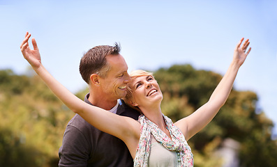 Image showing Couple, freedom and smile with love outdoors for honeymoon vacation, together and arms up for happiness. Man, woman and relationship with care for romance, marriage and support with trust for bonding