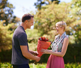 Image showing Smile, couple and present of flowers in nature outdoor, bonding and date on valentines day. Bouquet, man and woman with gift for love, care and romantic connection of people laughing at park together