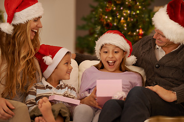 Image showing Parents, living room and christmas with gift, surprise and joy with home on sofa. Family, children and celebration with present, gratitude and thank you with happiness or appreciation for holiday