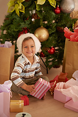 Image showing Boy, child and face with gift on christmas on floor in living room of home with happiness or santa hat. Kid, person and smile with present for celebration, tradition or holiday in lounge of apartment