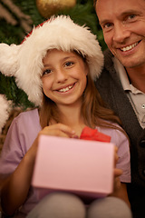 Image showing Christmas, portrait and child with gift box, dad and celebration together with happy surprise. Holiday, father and daughter smile in living room for present giving, festive xmas and love in home.