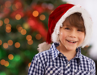 Image showing Christmas, portrait and happy child in home with bokeh for festive celebration, party and holiday. Face, smile and boy in hat for xmas, laughing or excited facial expression in house in Australia